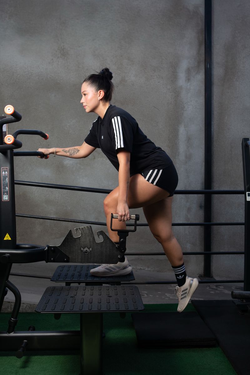 Alumna entrena en la escaladora junto al muro de hormigón del gimnasio