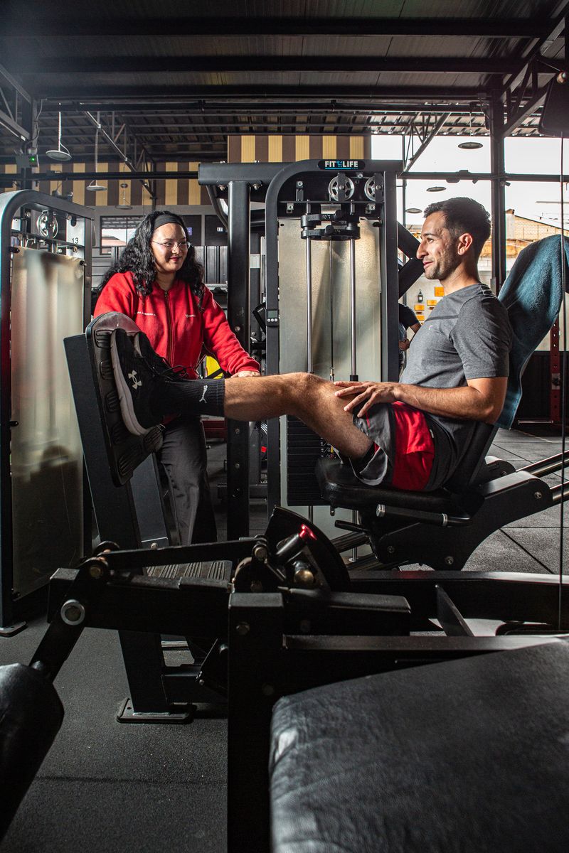 Una profesional de Fit4Life acompaña a un alumno en la extensión de piernas