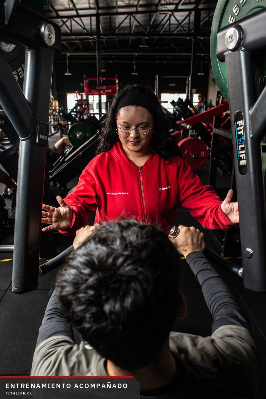 Una profesional de Fit4Life le explica un ejercicio a un alumno en la máquina